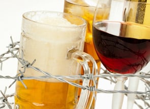 Bierglas und Weinglas hinter dem Stacheldrahtzaun