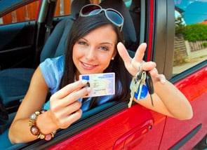 Fröhliche Frau hält die Fahrerlaubnis und die Autoschlüssel in der Hand
